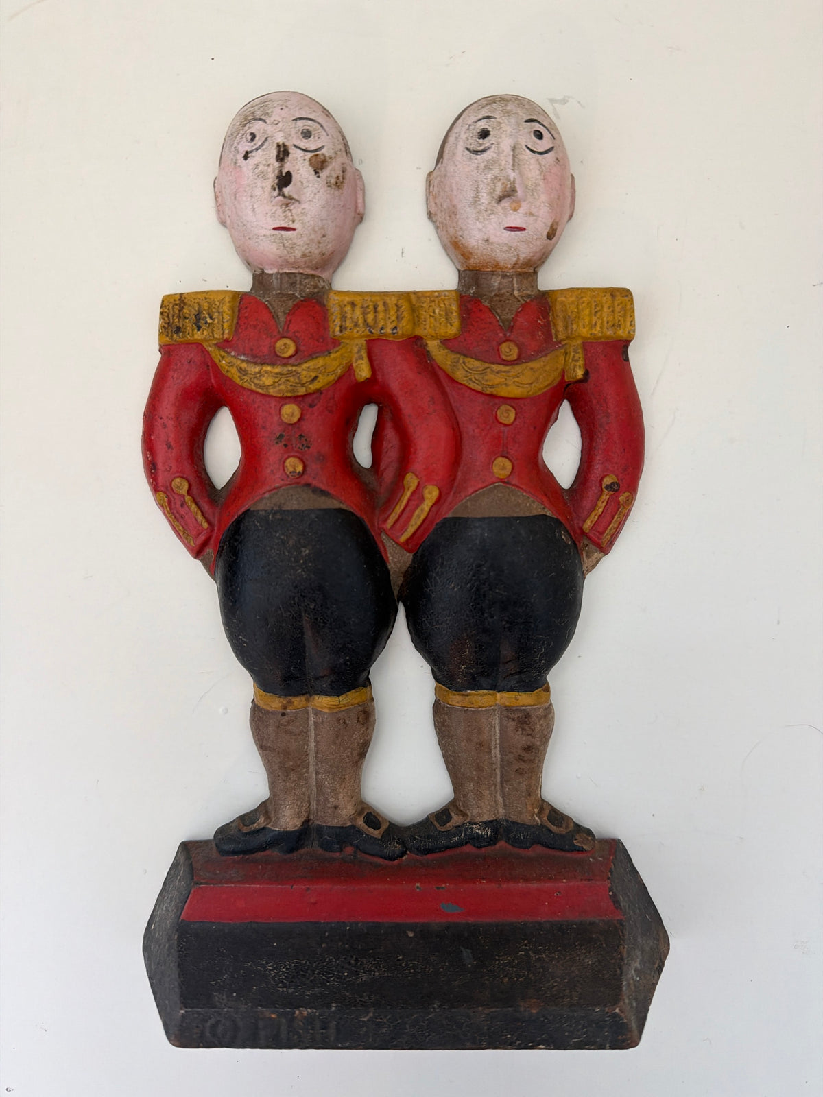 Antique Hubley cast iron doorstop featuring two Anne Fish-designed footmen in matching red coats and gold braid, front view